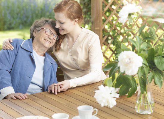 Happy grandmother enjoying time with friendly nurse on the terrace of sanatorium